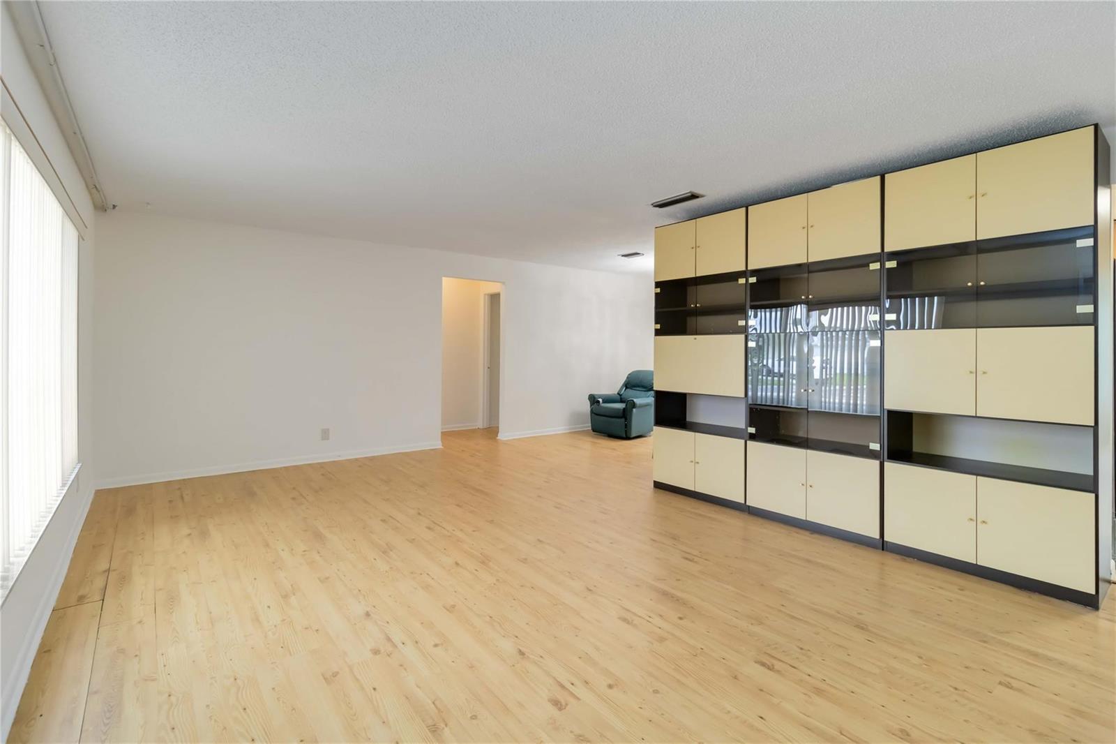 A living room with light wood flooring, white walls, and a large modular storage unit — 735 NW 73rd Terrace, Margate FL 33063, MARGATE, FL
