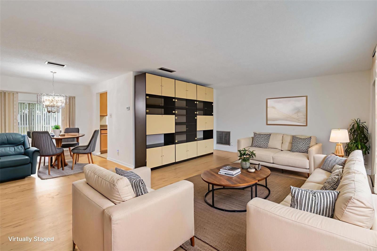 A virtually staged living room features light wood floors, a large storage unit, and neutral furniture — 735 NW 73rd Terrace, Margate FL 33063, MARGATE, FL