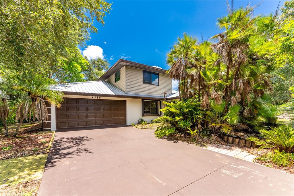 A two-story house with a brown garage door and palm trees in the front yard — 4880 WECOMA AVENUE, NORTH PORT, FL