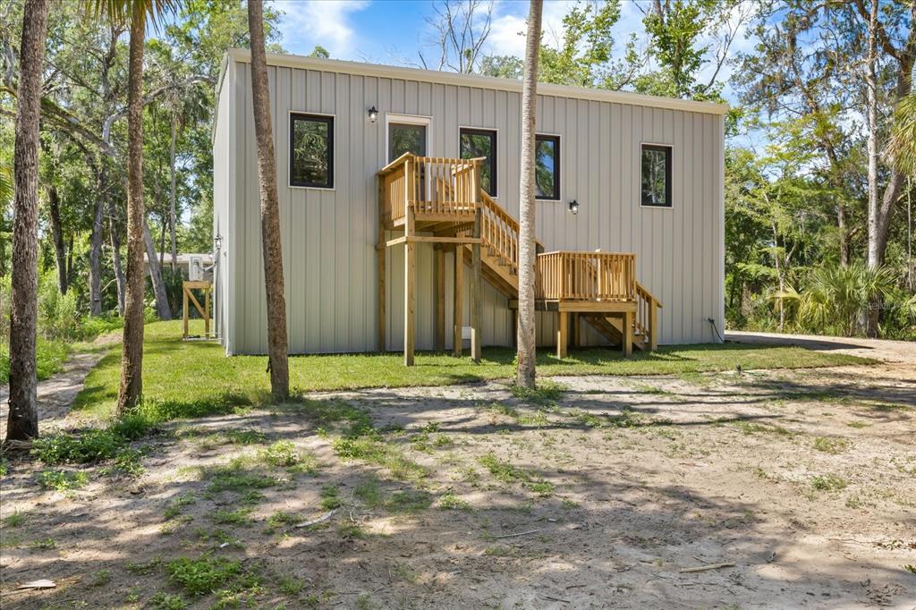 A gray front door with a glass panel is centered between two windows on a deck — 10408 W LARCHWOOD STREET, HOMOSASSA, FL