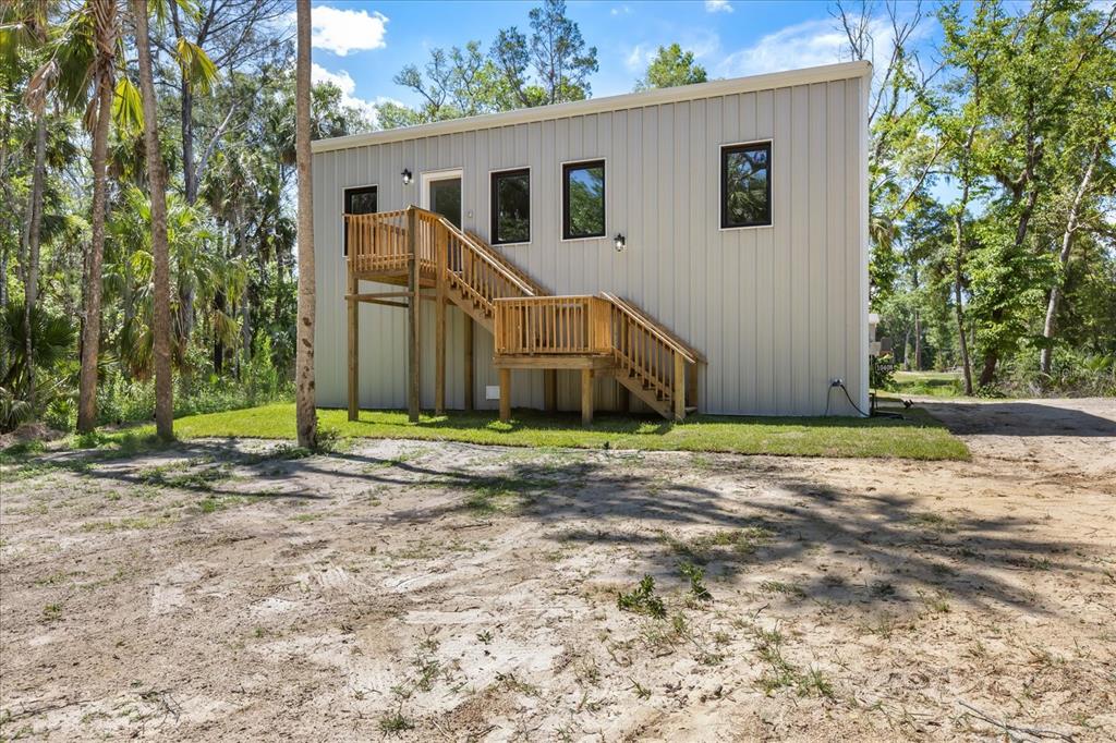 An exterior view of a wooden staircase leading to a deck beside a metal building — 10408 W LARCHWOOD STREET, HOMOSASSA, FL