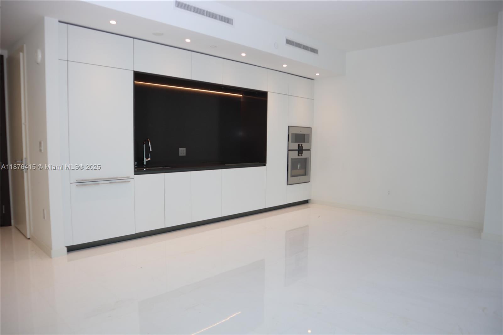 A modern kitchen features white cabinetry, a black backsplash, and high-gloss white flooring — 300 Biscayne Blvd Way # 2308, Miami FL 33131, MIAMI, FL