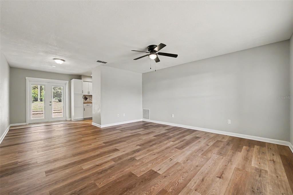 An open-concept living room features light gray walls, wood-look flooring, and a ceiling fan — 756 SHAFTON AVENUE, DELTONA, FL