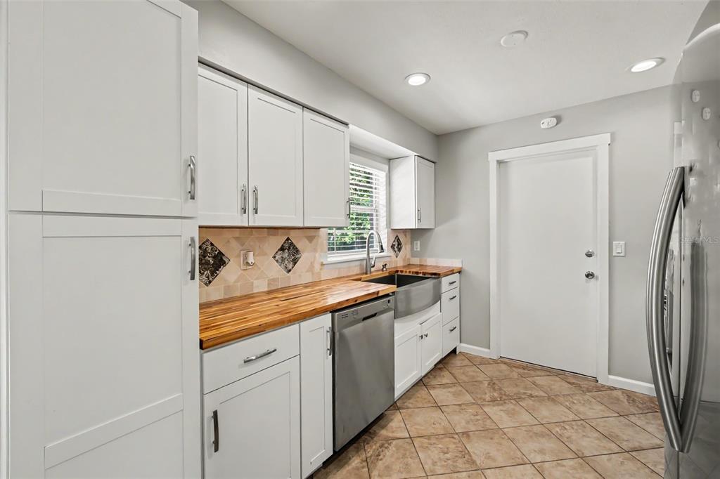 A kitchen features white cabinets, a wood countertop, a stainless steel dishwasher, and tile flooring — 756 SHAFTON AVENUE, DELTONA, FL