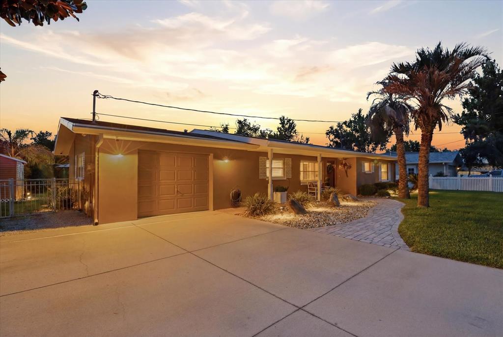 A single-story house with a garage, paved driveway, and landscaped front yard at sunset — 1302 SE PARADISE AVENUE, CRYSTAL RIVER, FL