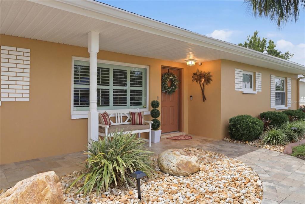 The exterior of a house features a tan stucco facade, a front porch, and landscaping — 1302 SE PARADISE AVENUE, CRYSTAL RIVER, FL