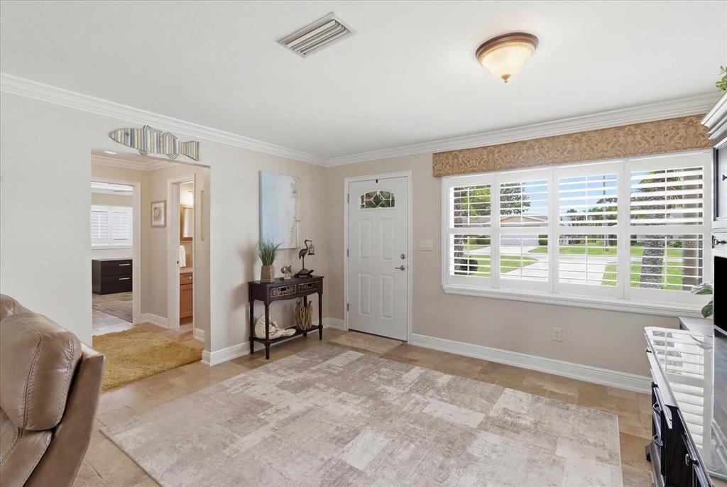 A living room features tile flooring, a large area rug, plantation shutters, and an entryway — 1302 SE PARADISE AVENUE, CRYSTAL RIVER, FL