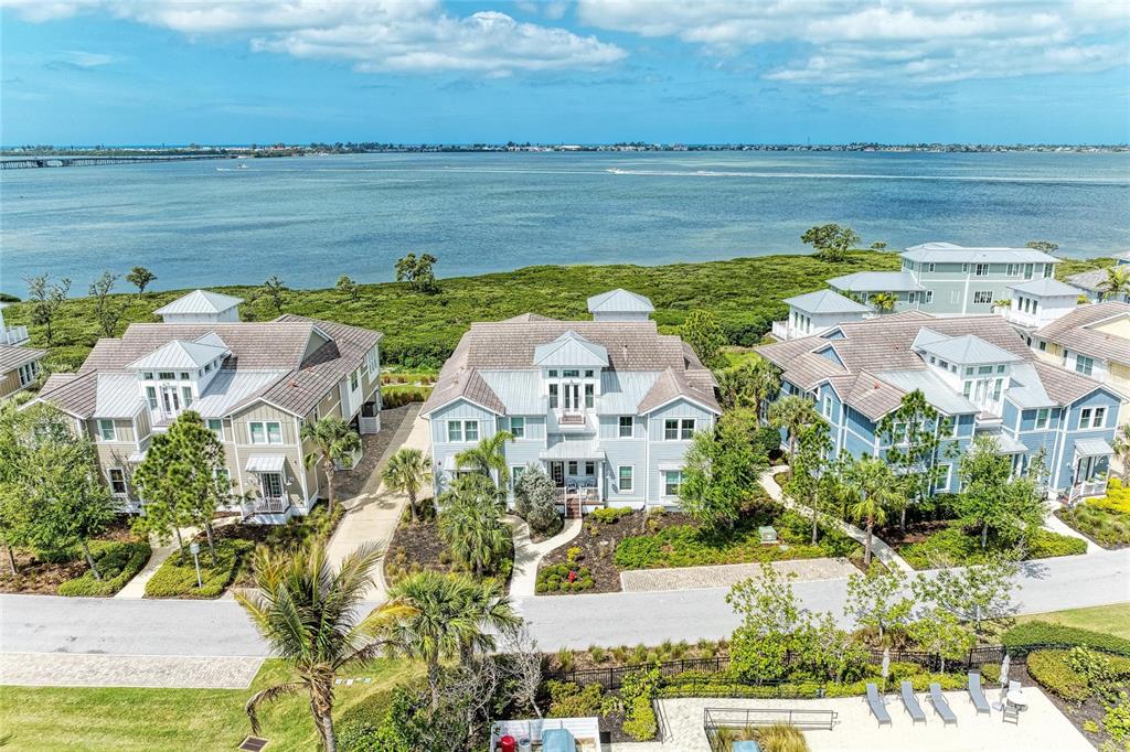 An aerial view shows three multi-story coastal houses situated along a waterfront with mangroves — 342 CASTAWAY CAY DRIVE UNIT 201, BRADENTON, FL