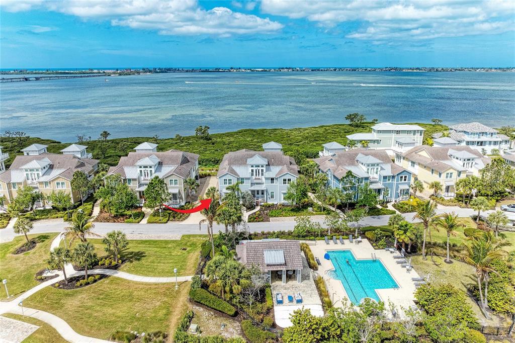 An aerial view shows several multi-story houses near a pool and a large body of water — 342 CASTAWAY CAY DRIVE UNIT 201, BRADENTON, FL