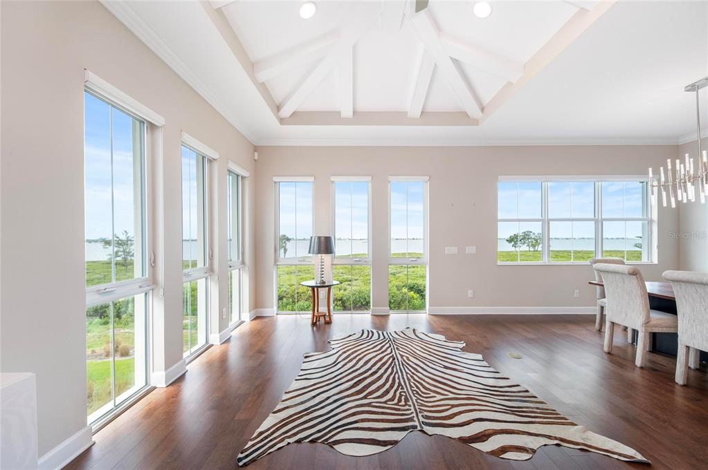 A bright dining room with a coffered ceiling, hardwood floors, and large windows overlooking water — 342 CASTAWAY CAY DRIVE UNIT 201, BRADENTON, FL