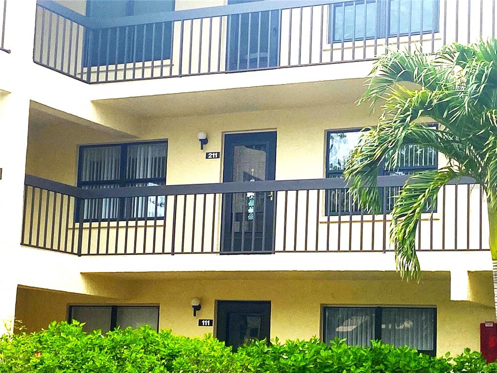 An exterior view of a multi-story apartment building with balconies and numbered unit doors — 425 30TH AVENUE W UNIT C211, BRADENTON, FL