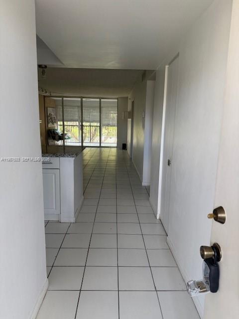 A view from an entryway looking down a tiled hallway toward a bright living area — 3910 Inverrary Blvd # B, Lauderhill FL 33319, LAUDERHILL, FL