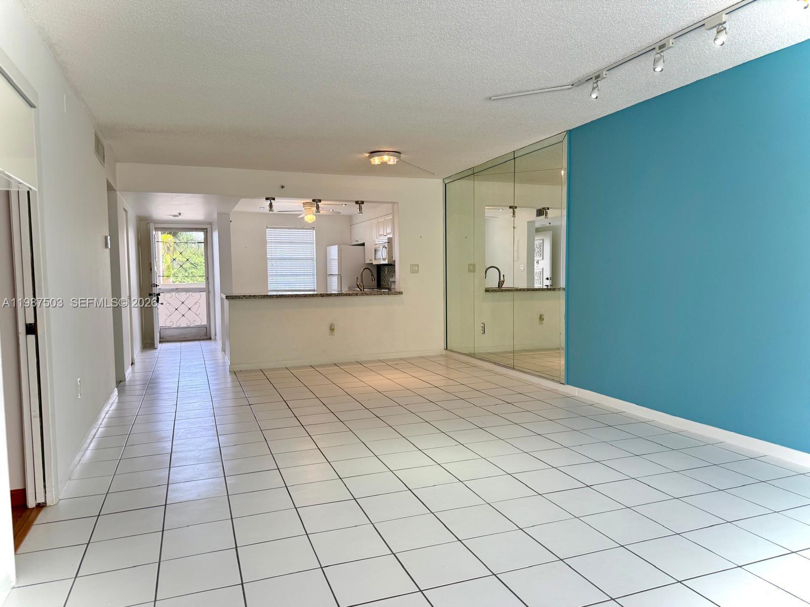 An open living area features white tile floors, a mirrored wall, and a blue accent wall — 3910 Inverrary Blvd # B, Lauderhill FL 33319, LAUDERHILL, FL