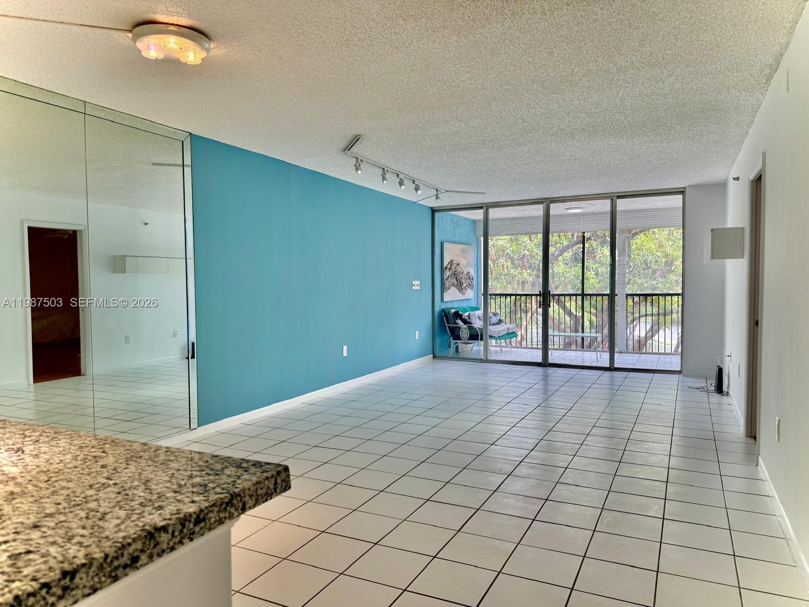 A living room features white tile floors, a blue accent wall, and a glass balcony door — 3910 Inverrary Blvd # B, Lauderhill FL 33319, LAUDERHILL, FL