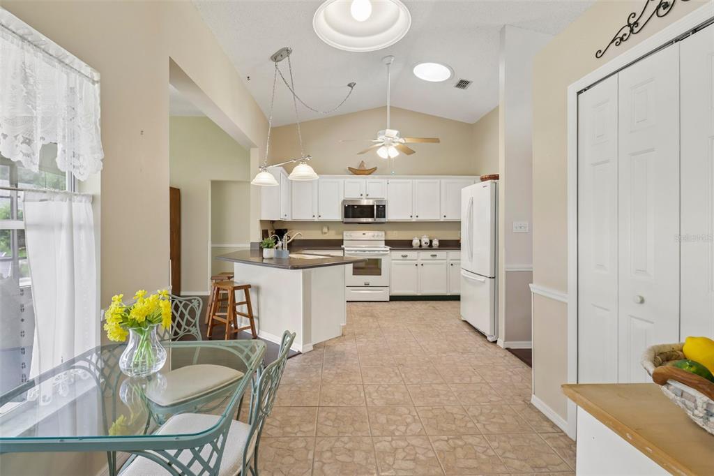 A kitchen with white cabinets, a breakfast bar, and a dining area with a glass table — 4529 PEACH TREE STREET, LEESBURG, FL