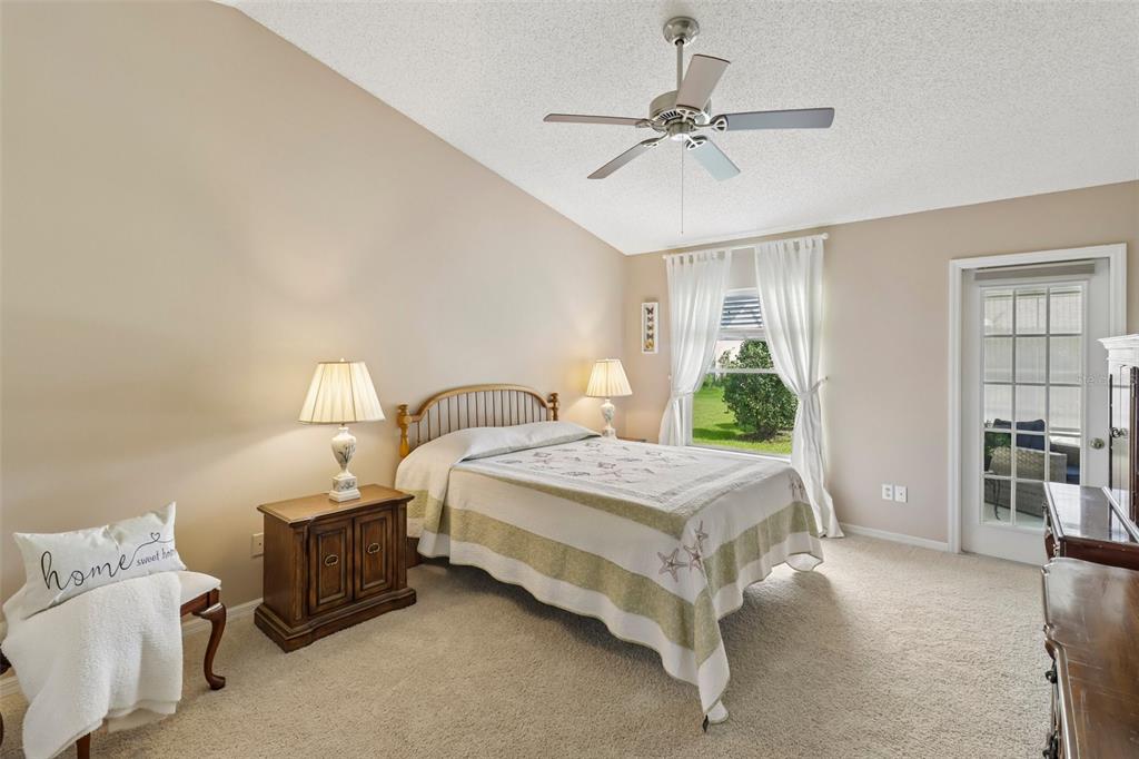 A bedroom features a queen bed, a wooden nightstand, a ceiling fan, and a glass door — 4529 PEACH TREE STREET, LEESBURG, FL
