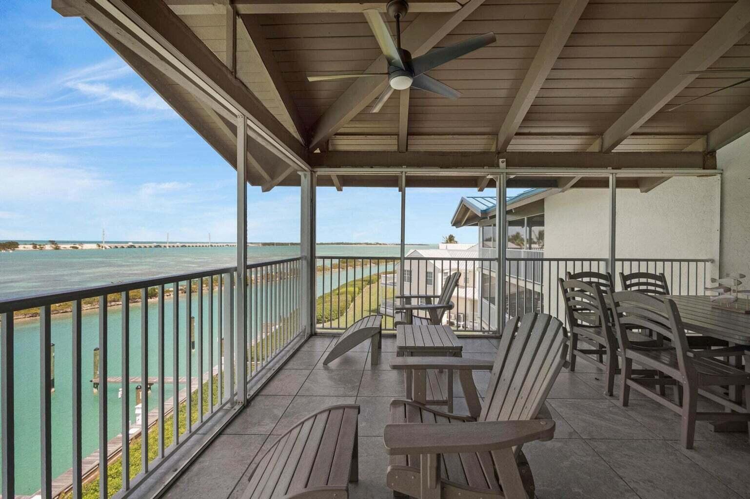 A screened-in balcony features tiled flooring, outdoor furniture, and a view of the water — 4402 Marina Villa Drive, Marathon FL 33050, MARATHON, FL