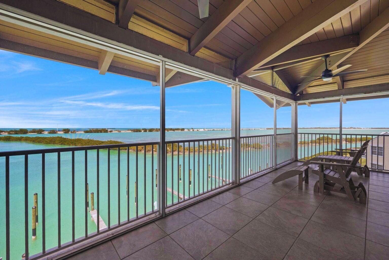 A screened-in balcony with tiled flooring overlooks a turquoise bay with a distant island — 4402 Marina Villa Drive, Marathon FL 33050, MARATHON, FL