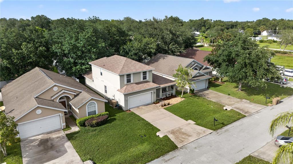 An aerial view shows three suburban houses with driveways and lawns on a residential street — 2020 BRIARCLIFF CIRCLE, MOUNT DORA, FL