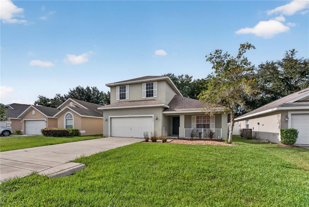 A two-story suburban house features a concrete driveway, a two-car garage, and a front porch — 2020 BRIARCLIFF CIRCLE, MOUNT DORA, FL
