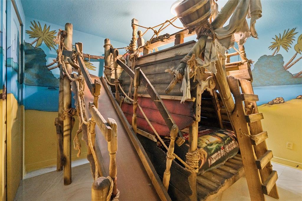 A child's bedroom features a custom wooden pirate ship bunk bed with a built-in slide — 7605 BROOKHURST LANE, KISSIMMEE, FL