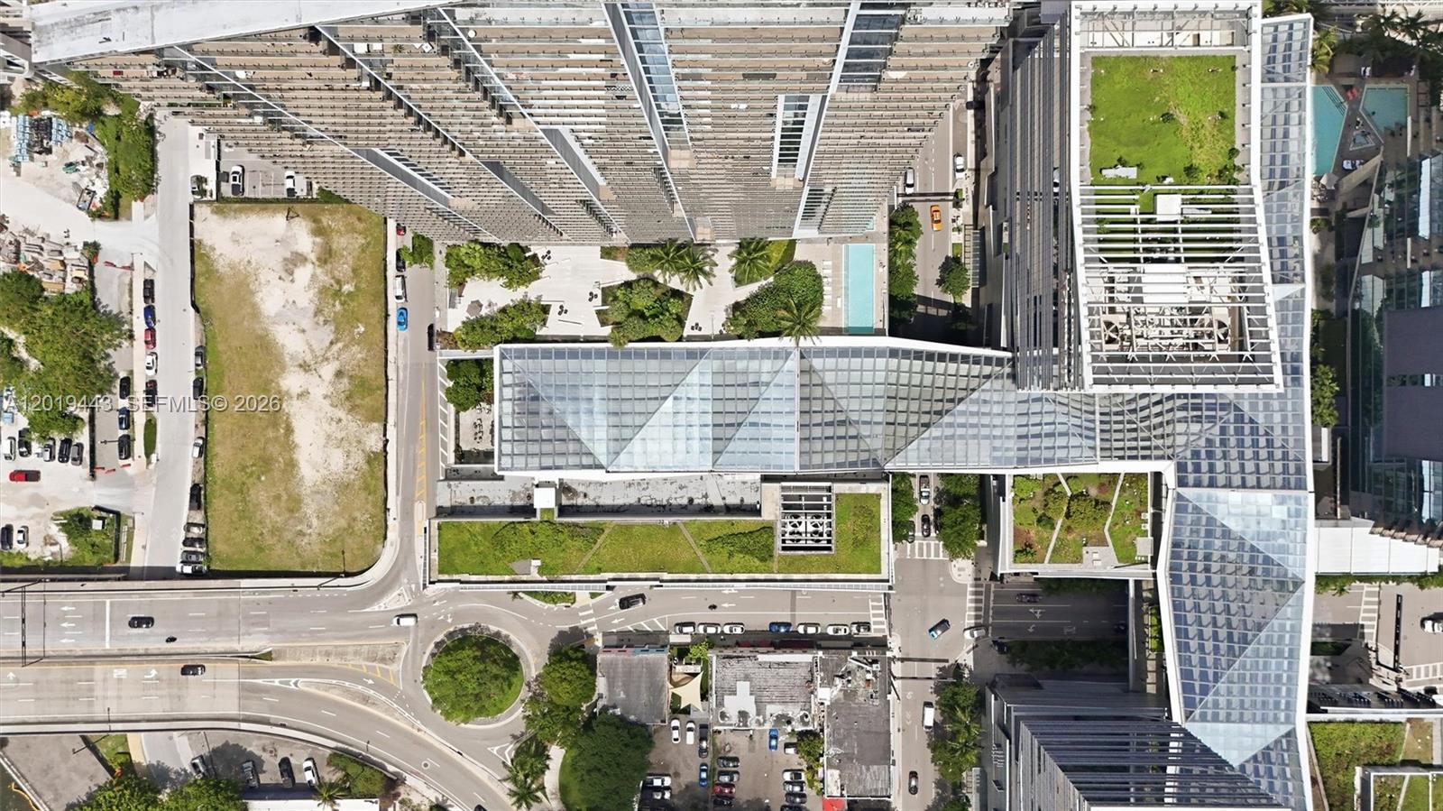 An aerial view shows a large building complex with a glass-roofed atrium and green roofs — 68 SE 6th St # 2702, Miami FL 33131, MIAMI, FL