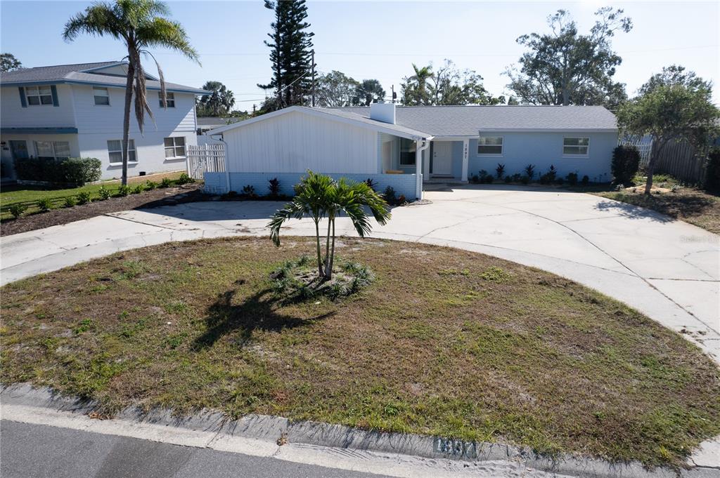 A light blue single-story house features a circular driveway and a small palm tree — 1897 DOLPHIN BOULEVARD S, ST PETERSBURG, FL