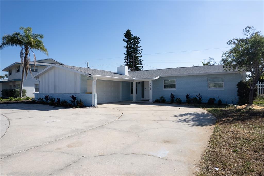 A light blue, single-story brick house with a large concrete driveway and a palm tree — 1897 DOLPHIN BOULEVARD S, ST PETERSBURG, FL