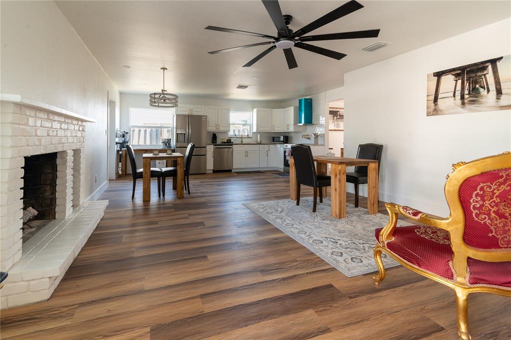 An open-concept kitchen and dining area features white cabinets, wood-look flooring, and a brick fireplace — 1897 DOLPHIN BOULEVARD S, ST PETERSBURG, FL