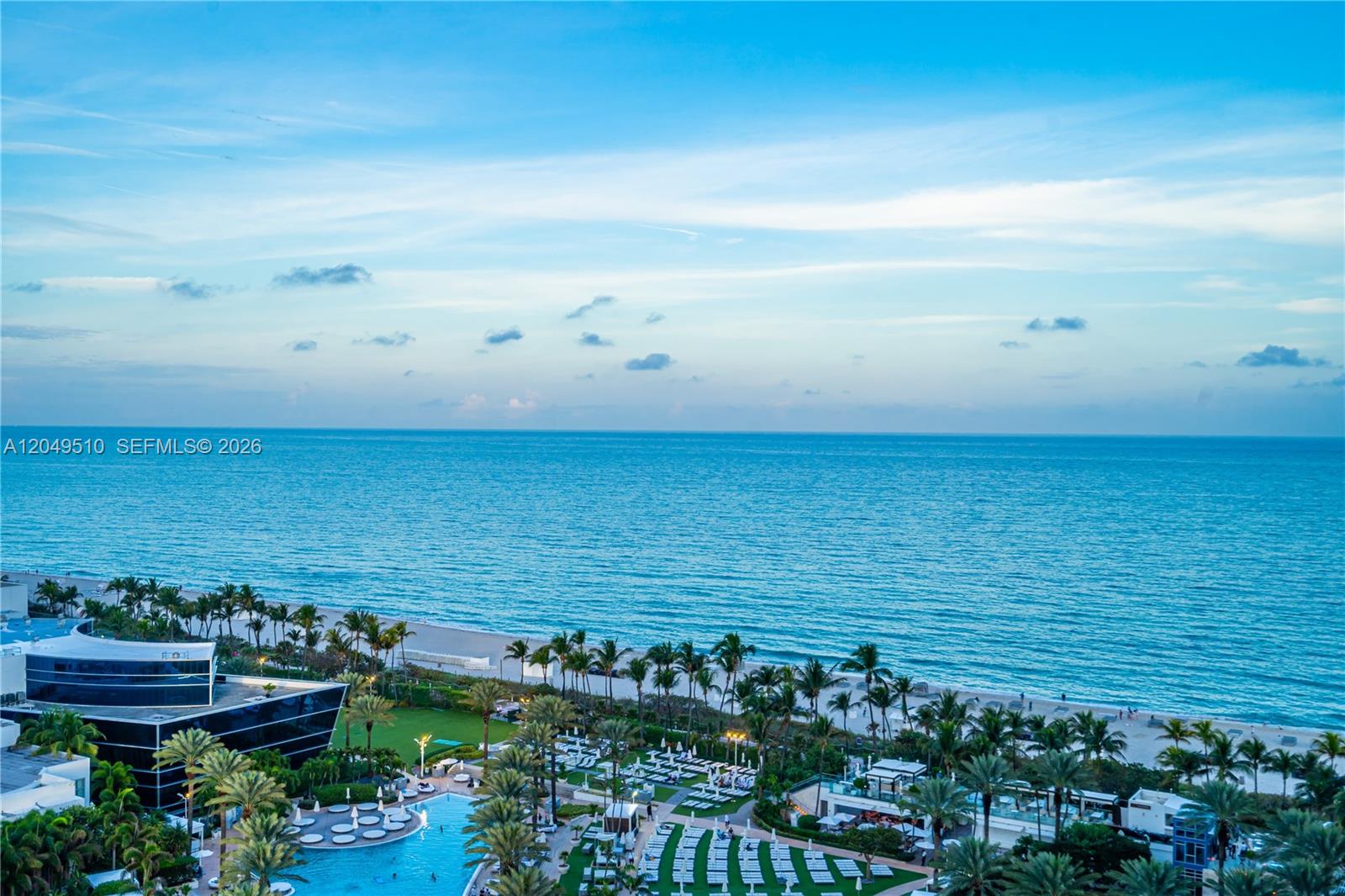 An aerial view shows a resort pool area, palm trees, and a beach by the ocean — 4401 Collins Ave # 1609, Miami Beach FL 33140, MIAMI BEACH, FL