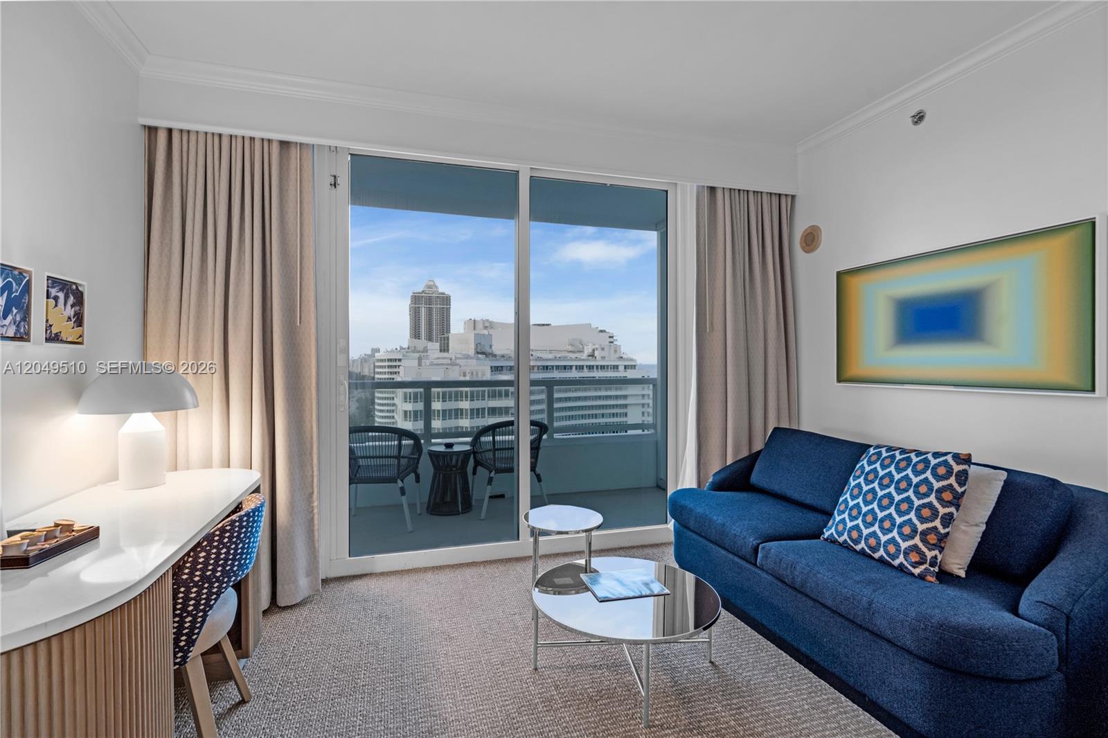 A hotel room features a blue sofa, a desk, and a balcony with city views — 4401 Collins Ave # 1609, Miami Beach FL 33140, MIAMI BEACH, FL