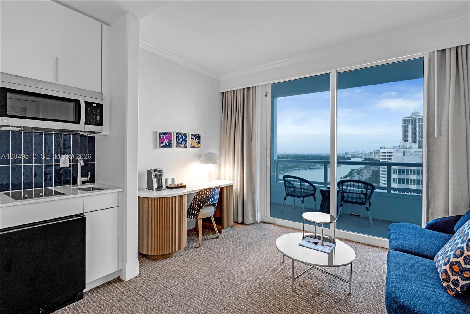 A hotel room features a kitchenette, a desk, a sofa, and a balcony with water views — 4401 Collins Ave # 1609, Miami Beach FL 33140, MIAMI BEACH, FL