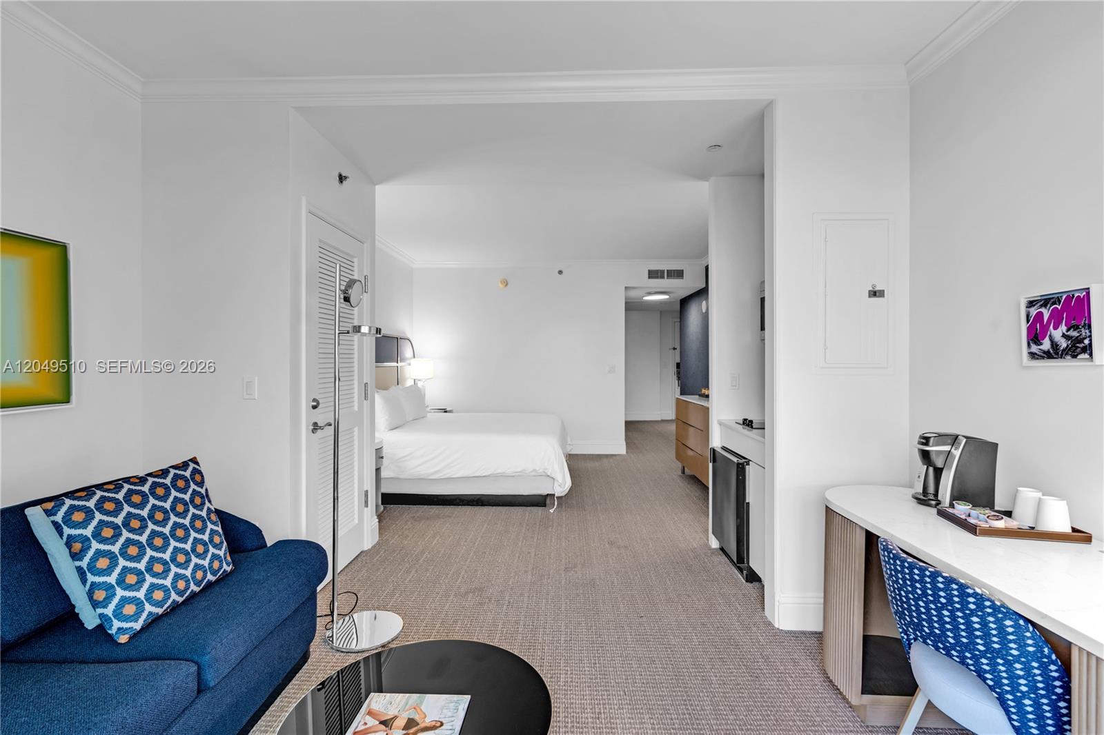This hotel room features a blue sofa, a bed, and a desk area with carpeting — 4401 Collins Ave # 1609, Miami Beach FL 33140, MIAMI BEACH, FL