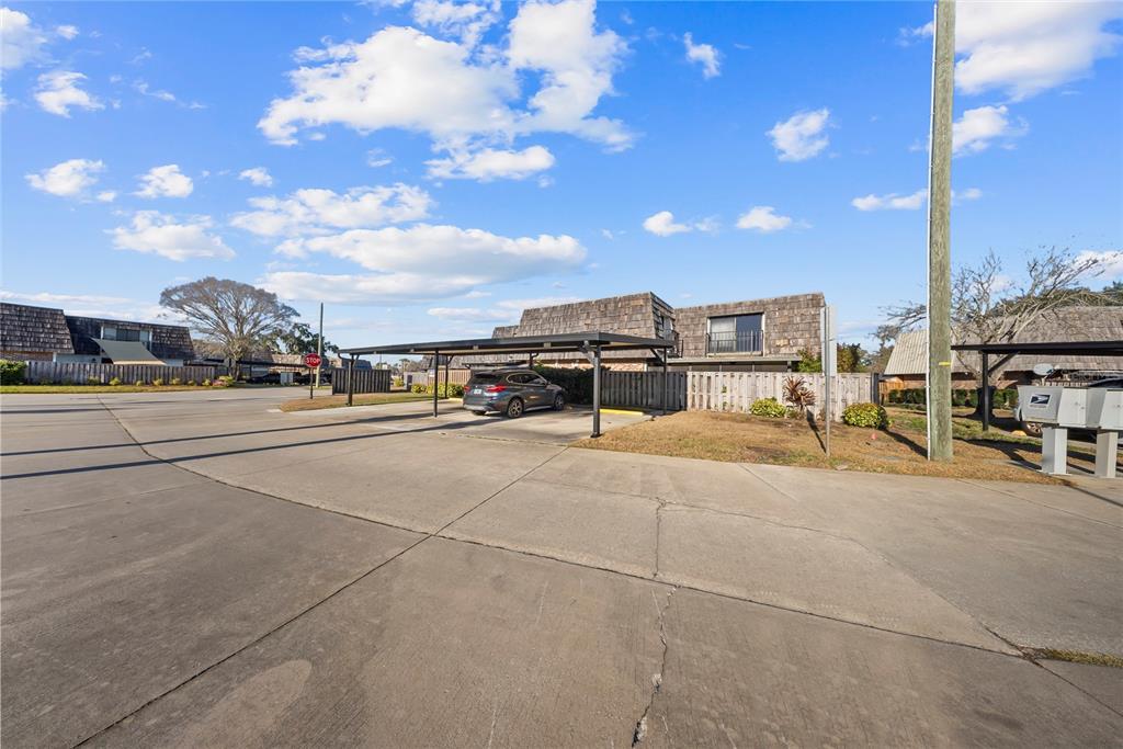 A paved parking lot with a covered carport and a gray SUV under a blue sky — 2920 PECAN AVENUE, LEESBURG, FL