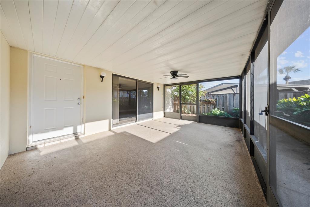 A covered screened-in patio with a concrete floor, ceiling fan, and sliding glass door — 2920 PECAN AVENUE, LEESBURG, FL