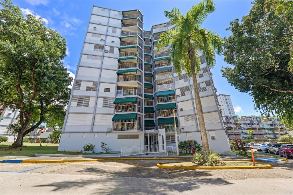 A multi-story residential apartment building with balconies and green awnings stands near a palm tree — 472 CALLE DE DIEGO UNIT 602 B, SAN JUAN, PR