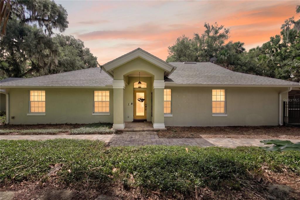 A single-story house with a light green exterior, a covered entryway, and a paved walkway — 16720 BEAUCLAIRE CT, TAVARES, FL