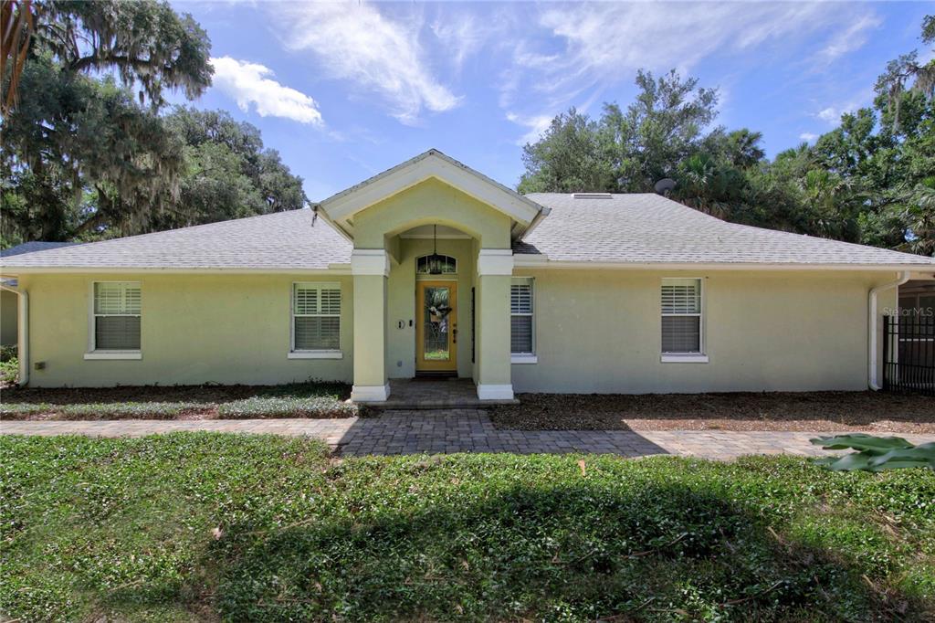 A single-story house with a light green exterior, a covered entryway, and a paved walkway — 16720 BEAUCLAIRE CT, TAVARES, FL