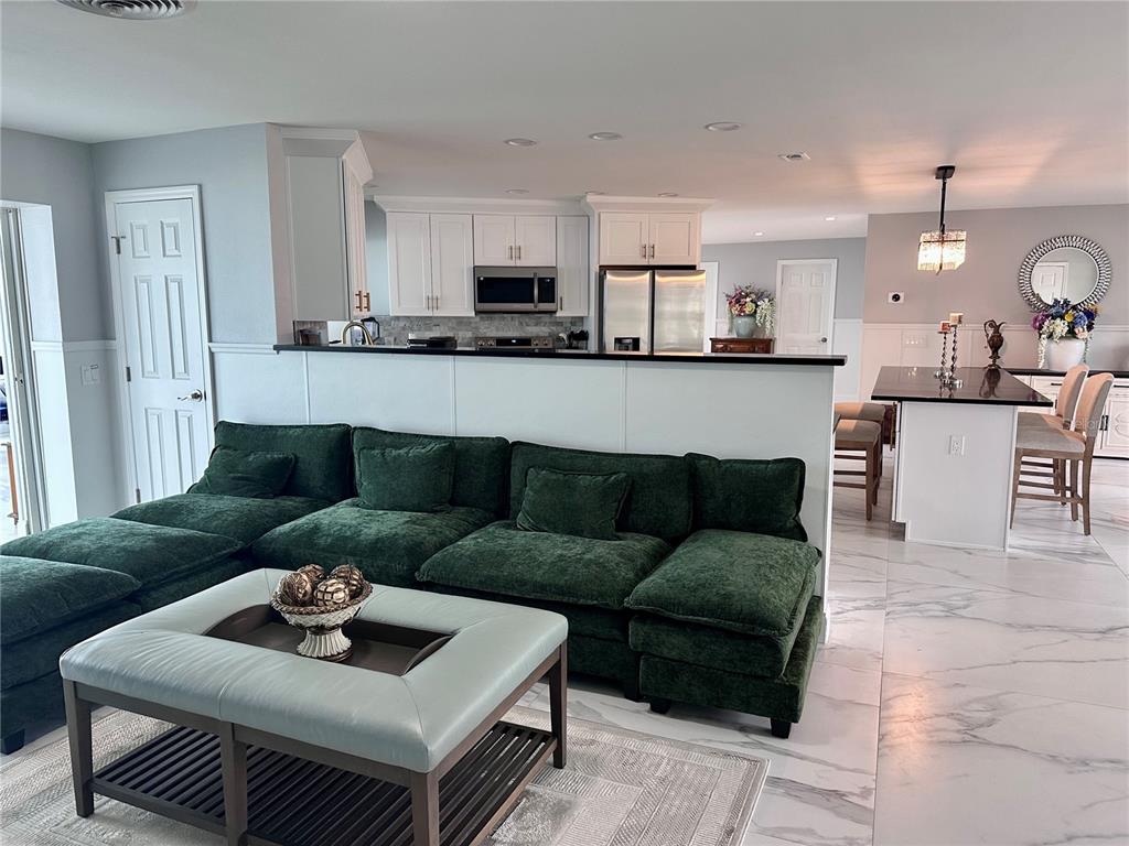 A living room with a green sectional sofa faces a kitchen with white cabinets — 12000 W BAYSHORE DRIVE, CRYSTAL RIVER, FL