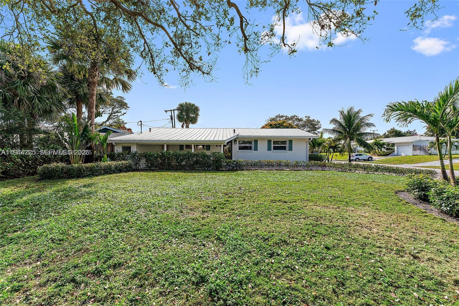 A single-story house with a white metal roof sits behind a large grassy lawn — 324 Tequesta, Tequesta FL 33469, TEQUESTA, FL