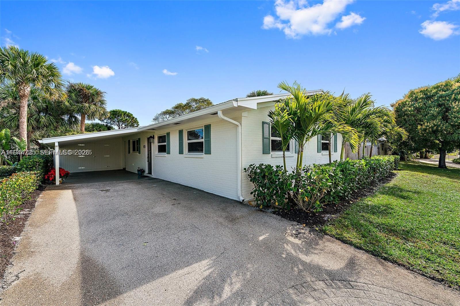 A white brick house features a carport, green shutters, and palm trees in the front yard — 324 Tequesta, Tequesta FL 33469, TEQUESTA, FL