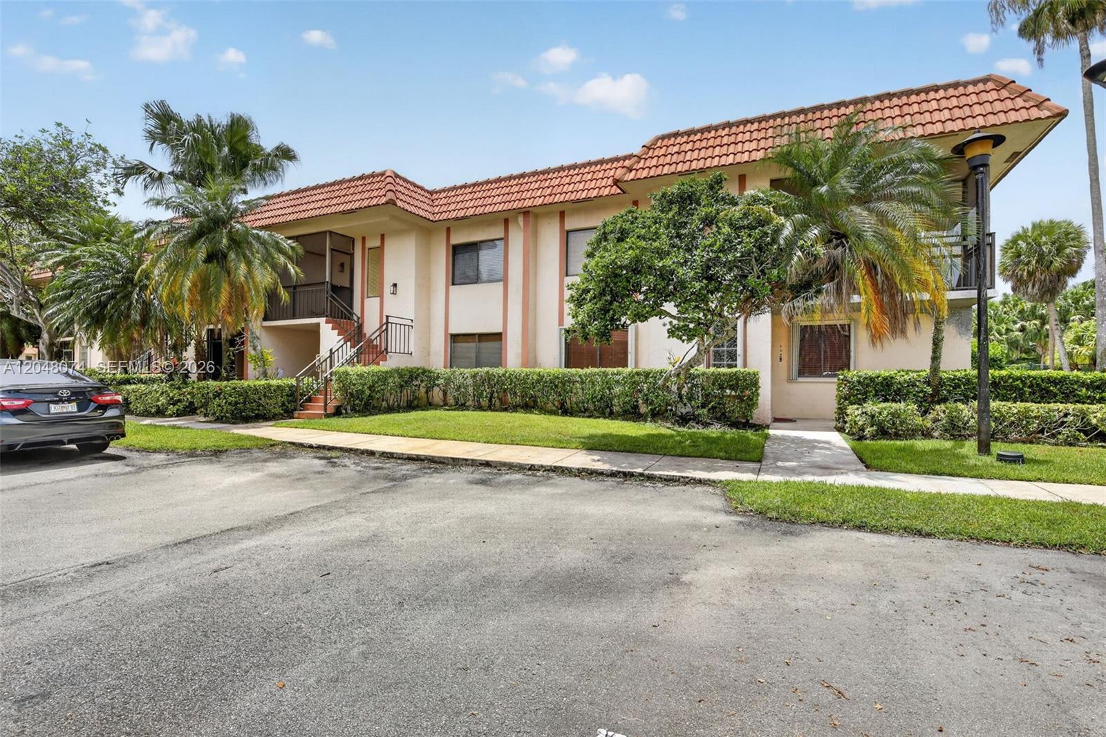 A two-story apartment building with a terracotta tile roof and palm trees in front — 359 Lakeview Dr # 102, Weston FL 33326, WESTON, FL
