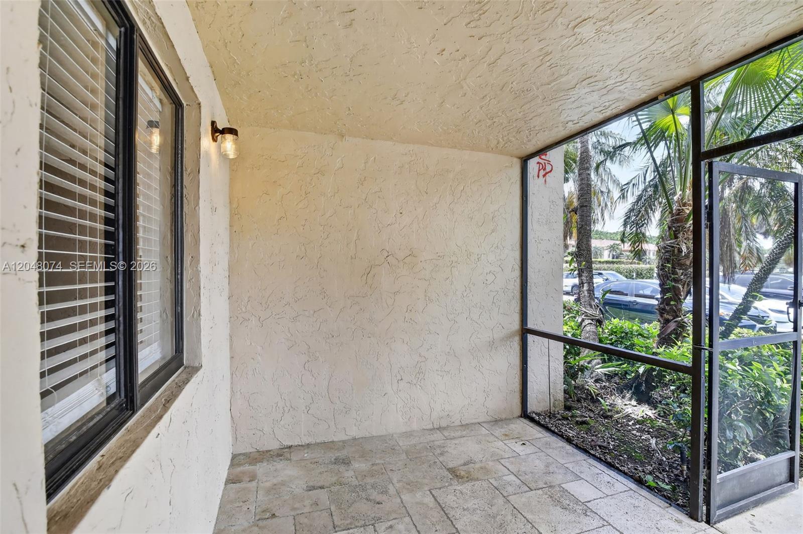 A covered patio features a textured wall, tiled flooring, and a screened-in view of landscaping — 359 Lakeview Dr # 102, Weston FL 33326, WESTON, FL