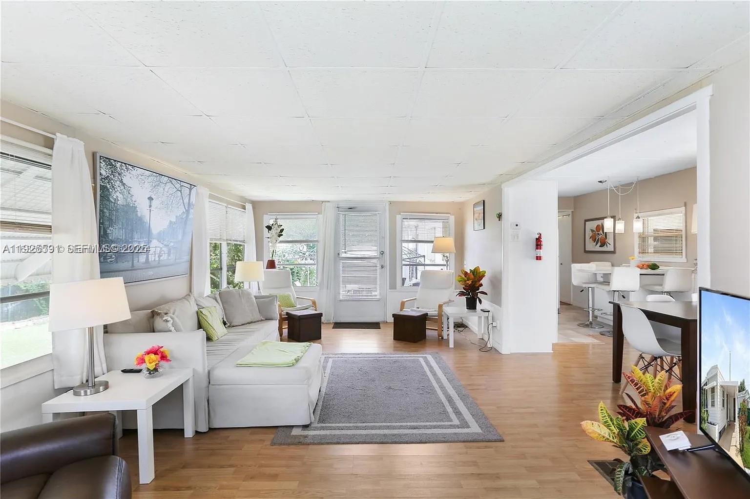 A living room with light wood floors, a white sectional sofa, and an adjacent dining area — 8616 SW 16th Pl, Davie FL 33324, DAVIE, FL