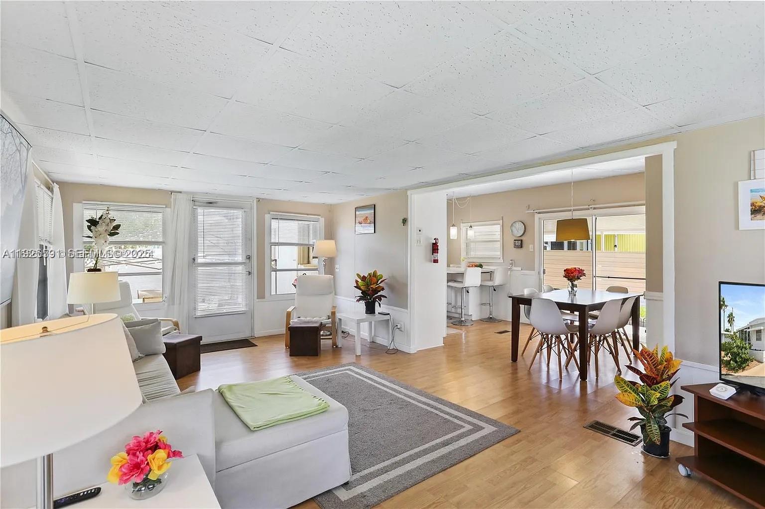A living room with light wood flooring flows into a dining area and kitchen — 8616 SW 16th Pl, Davie FL 33324, DAVIE, FL