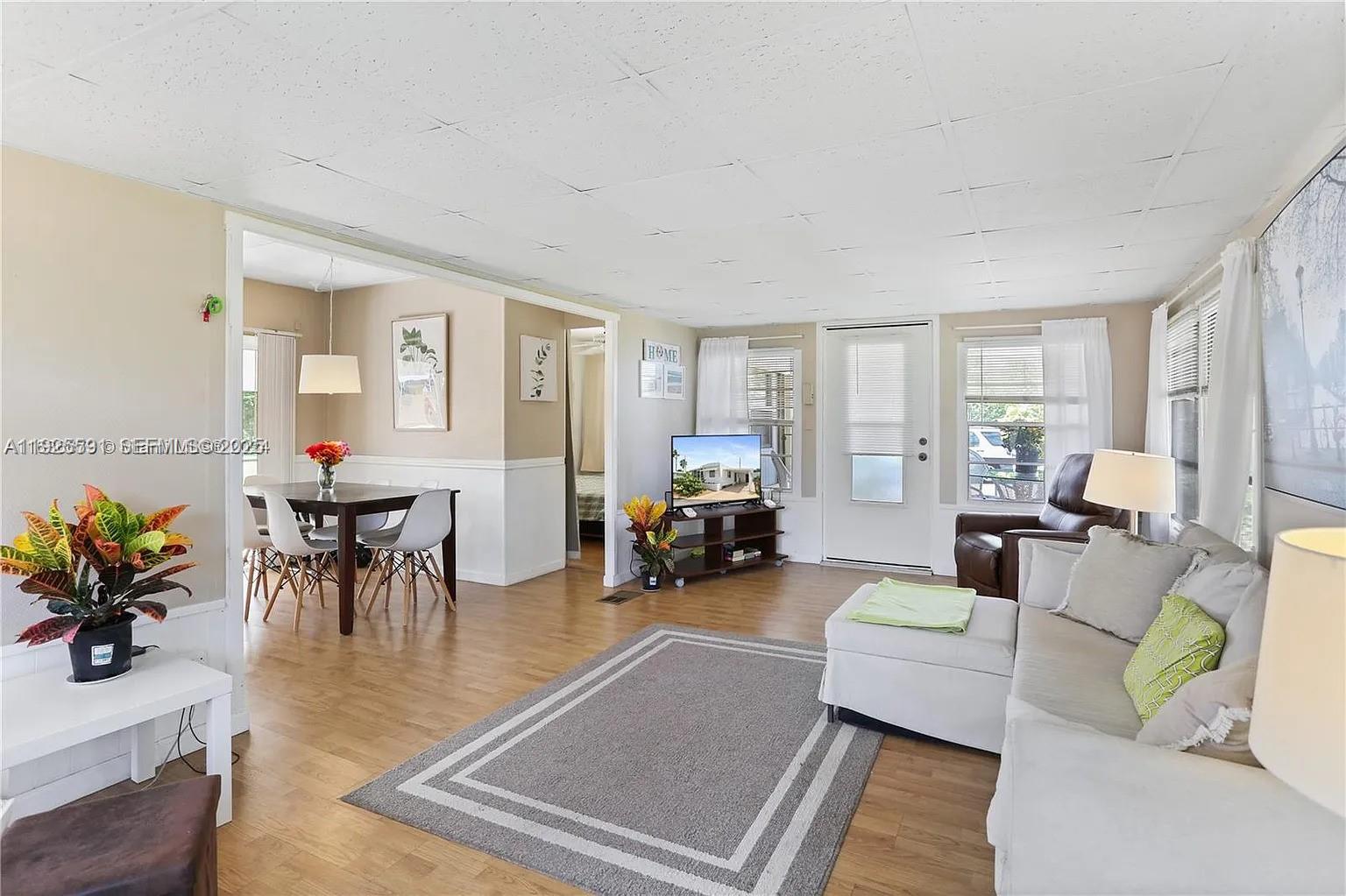 A living room and dining area feature light wood flooring, white walls, and neutral furniture — 8616 SW 16th Pl, Davie FL 33324, DAVIE, FL