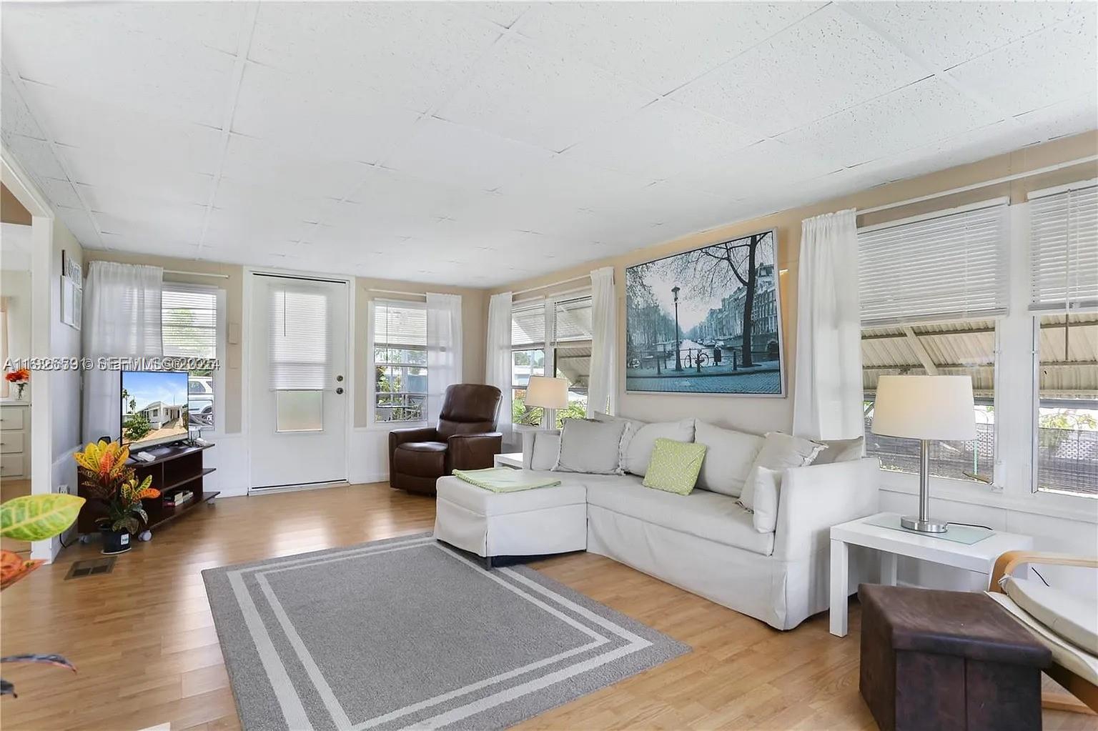A living room features light wood flooring, a white sectional sofa, and a large wall print — 8616 SW 16th Pl, Davie FL 33324, DAVIE, FL