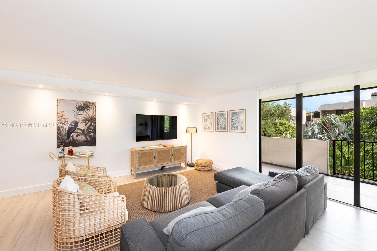 A living room features a gray sectional sofa, two wicker chairs, and a glass-topped coffee table — 181 Crandon Blvd # 306, Key Biscayne FL 33149, KEY BISCAYNE, FL