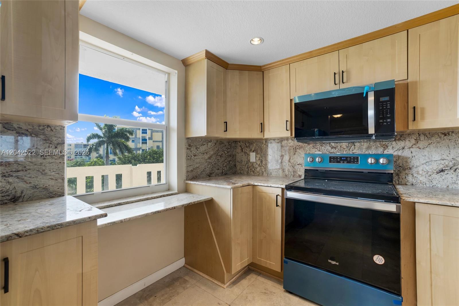 A kitchen features light wood cabinets, granite countertops, a black stove, and a window view — 321 SE 3rd St # 408, Dania Beach FL 33004, DANIA BEACH, FL