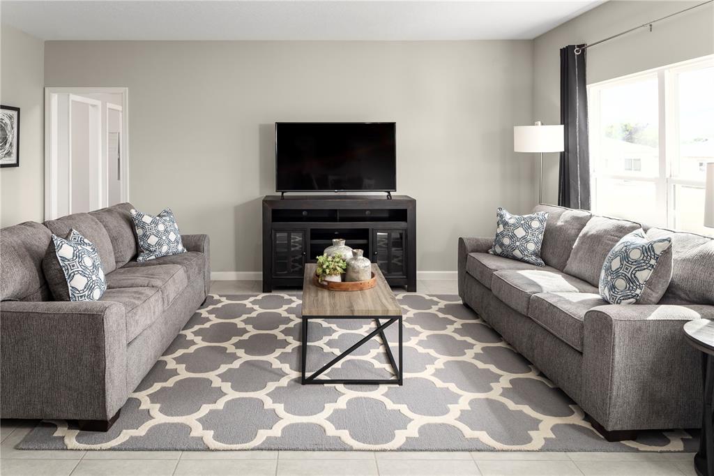 A living room features two gray sofas, a central coffee table, and a television console — 1113 LEXINGTON LANE, HAINES CITY, FL
